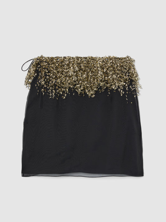 Crafted from sheer black silk, the Gold Fringe Skirt features a mini silhouette layered over a sleek slip lining, bringing effortless glamour to evening and occasion dressing.